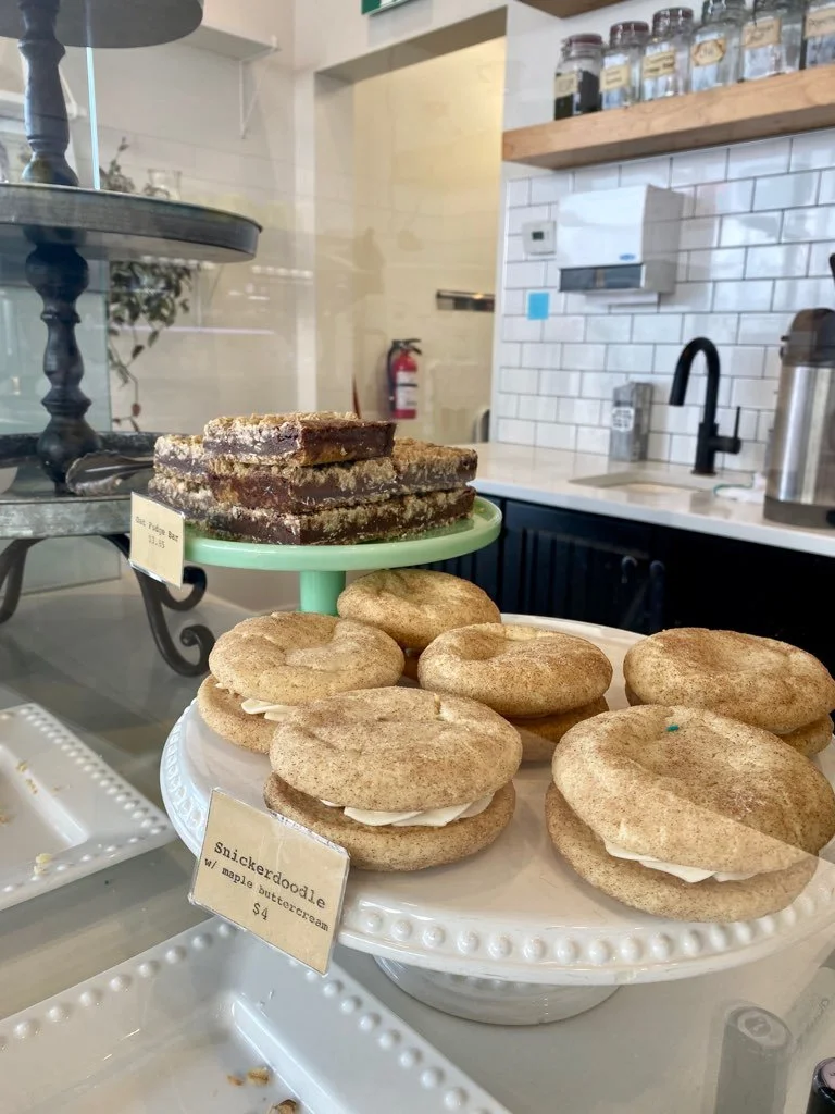 Snickerdoodle cookie sandwiches with maple buttercream and a chocolate fudge bar in the display case at Refuge
